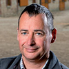 Dominique Pétillon qui fait partie du réseau d’agriculteurs « fermes de références » pose pour un portrait devant des caisses en bois.